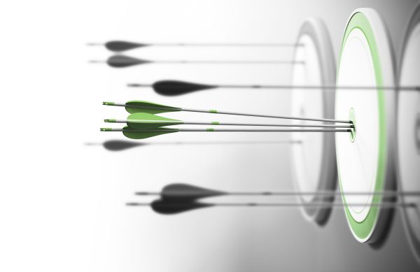 Three targets with focus on the one in the center and arrows hitting the center. Concept of competitive excellence and performance.