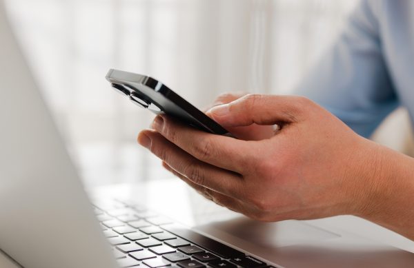 Businessman holding smartphone  and working on laptop