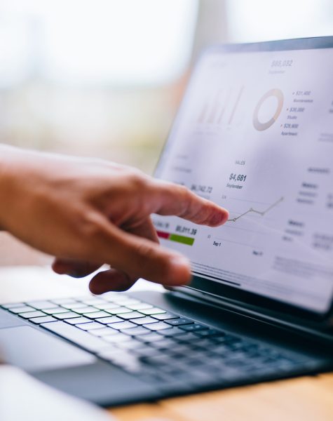 Close up photo of man hands pointing to a tablet screen and analyzing business report while sitting at restaurant table.